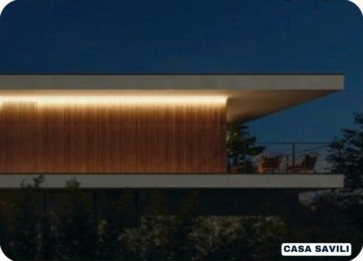 Casa Savili em linha horizontal, com forro de madeira iluminado e vista para a baía