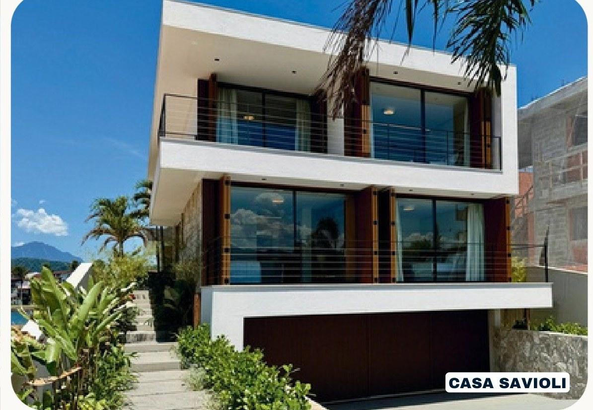 Casa Savioli em três pavimentos, com sacadas de vidro e palmeiras à frente