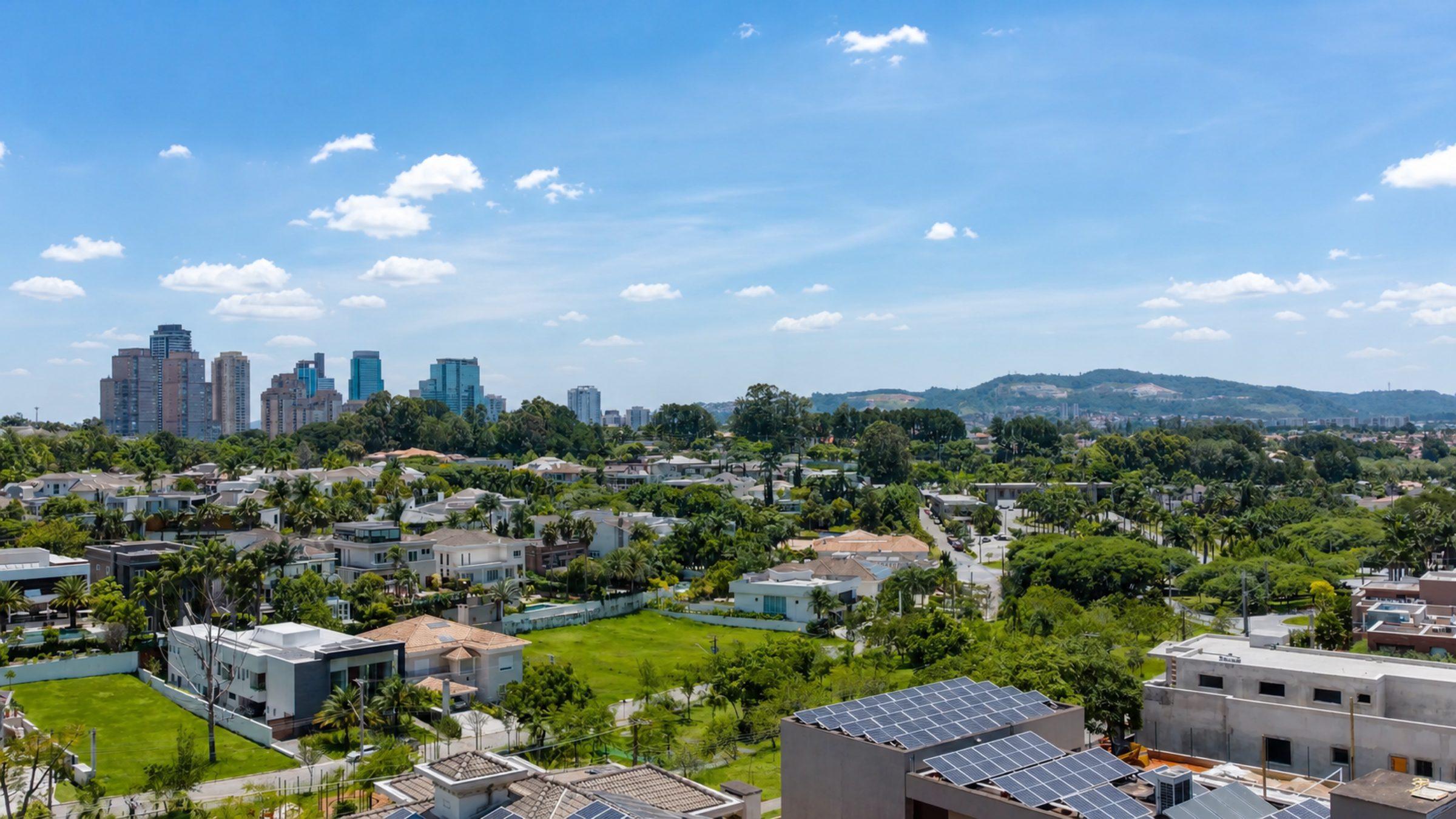 Vista aérea de condomínio fechado em Alphaville, com casas, jardins e o skyline ao fundo